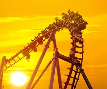 Thrill-seekers on a rollercoaster with the sun setting in the background